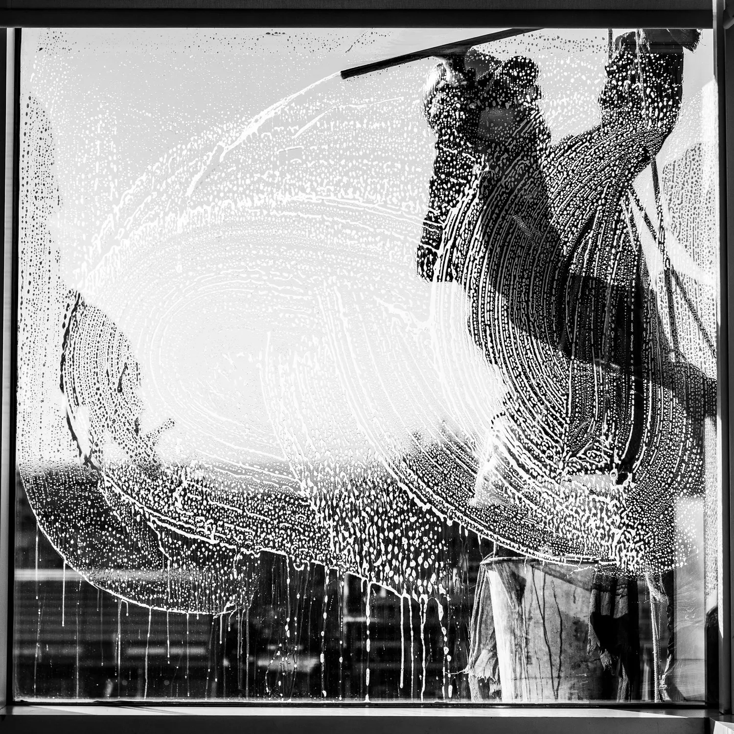 Keep clean - Reinigungs - Ein Arbeiter reinigt ein Fenster mit einem Abzieher und Seifenwasser.